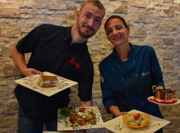 Luca and Monica holding plates of homemade Italian food.